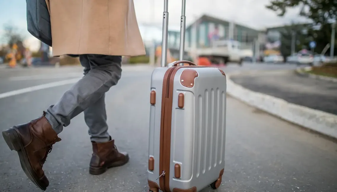 Pessoa puxando mala de viagem na calçada